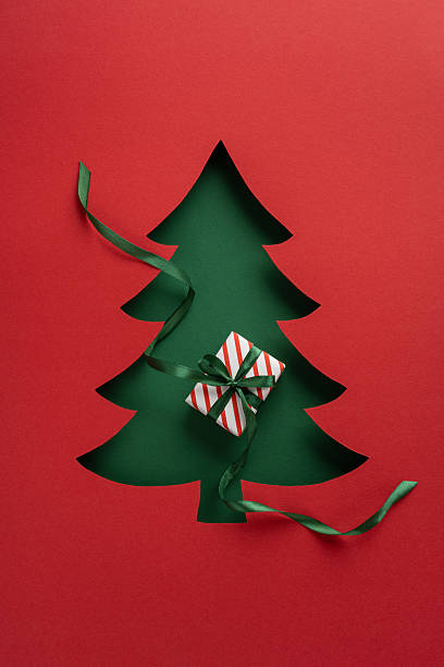istock A visually catching vertical cutout Christmas card illustration. Features a tree silhouette and gift 2232991984