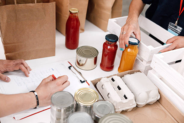 istock Hands Carefully Selecting Food Items for Community Donation Packages 2232999031