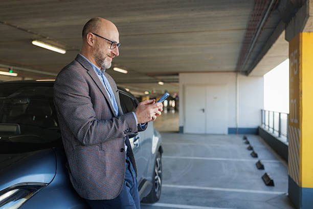 istock Business professional using smartphone in a parking garage during work break 2233001650