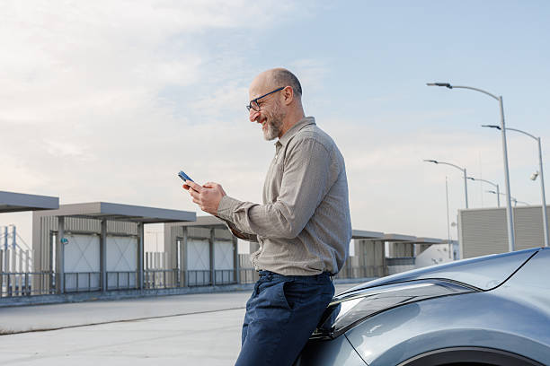 istock Businessman outside using smartphone near car on a sunny day 2233002087