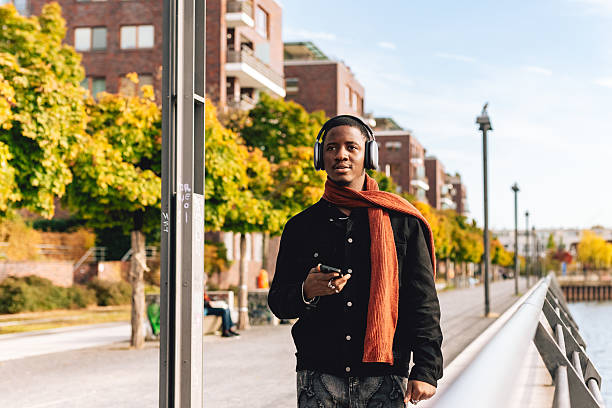 istock Young Man Walking on Riverside Promenade with Headphones 2233003511