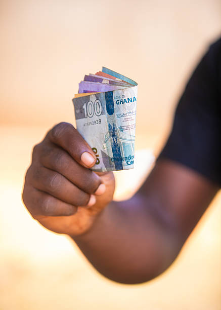 istock Black Hand holding showing Ghanaian Cedis notes outside daylight. 2233014938