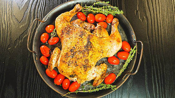 istock Whole roasted golden chicken with thyme and cherry tomatoes on board 2233016308