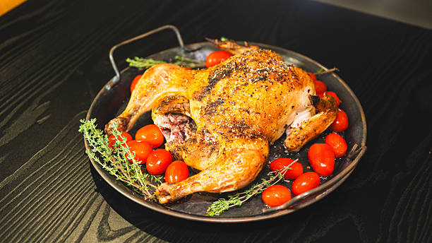 istock Whole roasted golden chicken with thyme and cherry tomatoes on board 2233016342