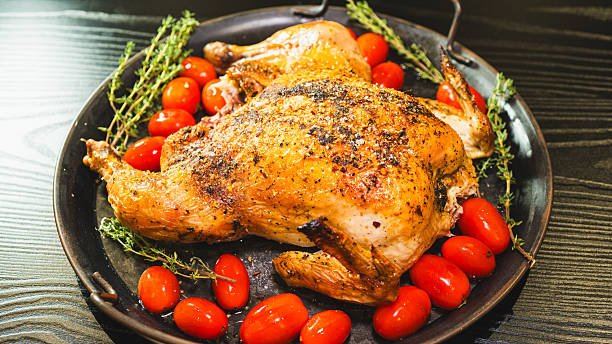 istock Whole roasted golden chicken with thyme and cherry tomatoes on board 2233016497