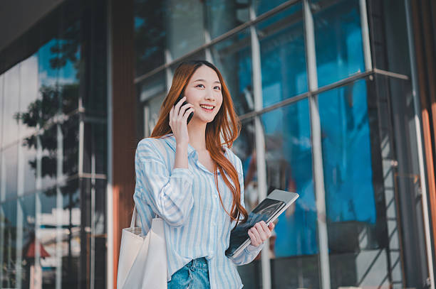 A woman is talking on her cell phone while holding a tablet