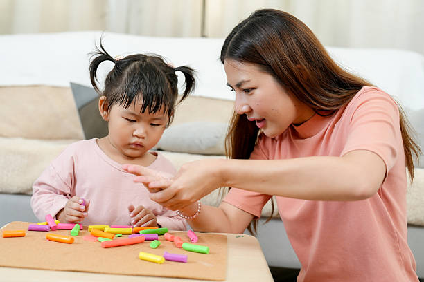 istock Asian single mother teaching little daughter assembling colorful clay pieces into creative shapes on table sitting together cozy bright living room early childhood education home learning 2233023685