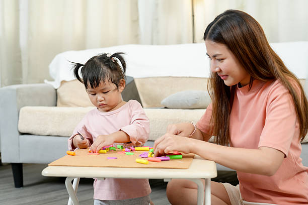 istock Asian single mother supporting little daughter creating colorful clay pieces on table sitting on floor cozy bright home living room early childhood development education creative activity 2233023687