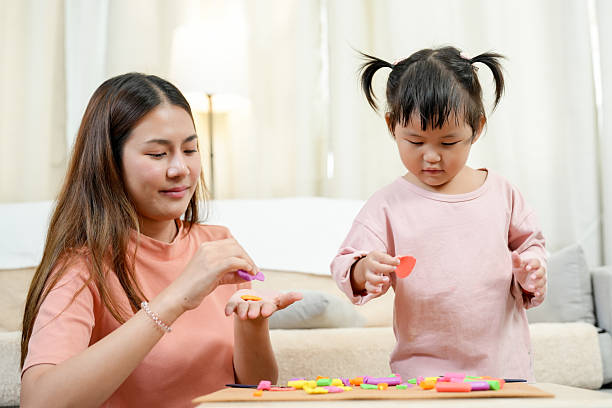 istock Asian single mother and little daughter sharing creative clay pieces while playing together building shapes cozy bright home early childhood education learning bonding artistic activity 2233023691