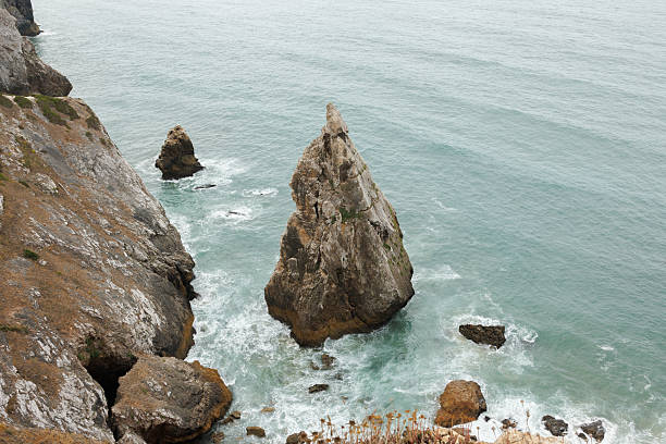 Steep cliffs and striking rock formations rise from the Atlantic Ocean at Ursa Beach near Cabo da Roca, Portugal’s rugged coastline. High quality stock photo