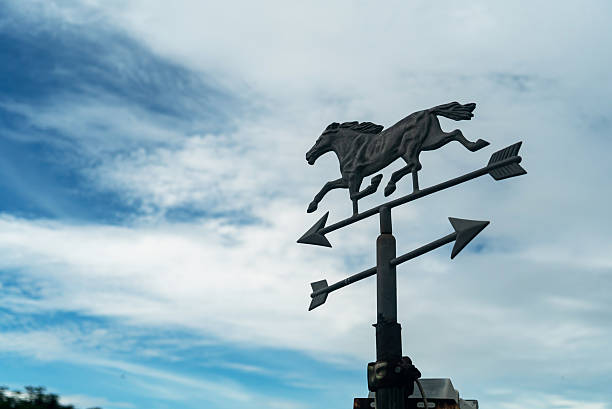 A stunning metal weather vane featuring a galloping horse against a backdrop of dynamic clouds. Ideal for illustrating themes of direction and nature.