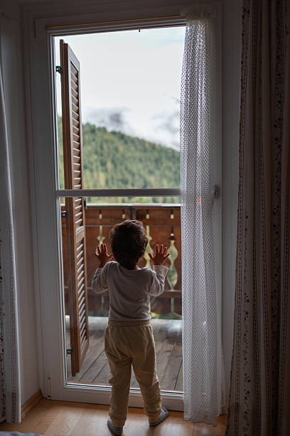 istock Curious child looking at mountain view through balcony door 2233040609