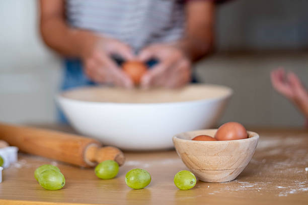 mom makes dough, cooks, on a wooden table, eggs, grapes, rolling pin, breaks an egg into a bowl