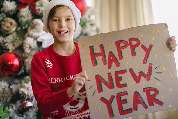 istock Happy boy in Christmas clothes is holding a christmas board. 2233048794