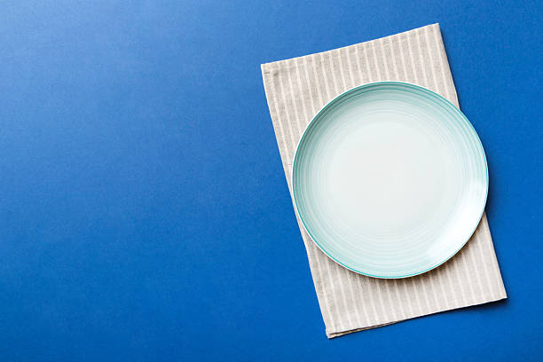 istock Top view on colored background empty round blue plate on tablecloth for food. Empty dish on napkin with space for your design 2233056276