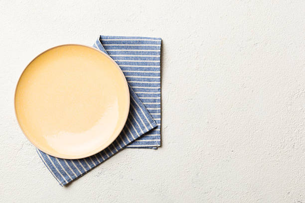 istock Top view on colored background empty round yellow plate on tablecloth for food. Empty dish on napkin with space for your design 2233056306