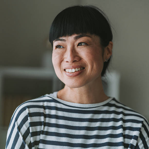 istock Smiling japanese woman touching chin while thinking and looking away 2233059704