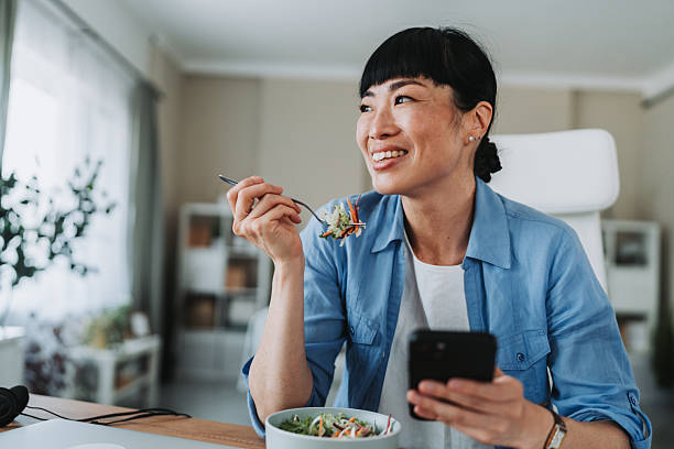 Freelancer eat a salad and use smart phone while working from home