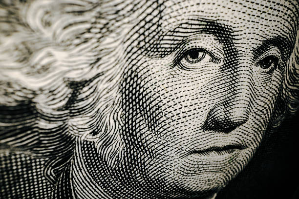 Abstract money. Unusual angles. President Washington looking grim on the One Dollar bill. Extreme close-up.