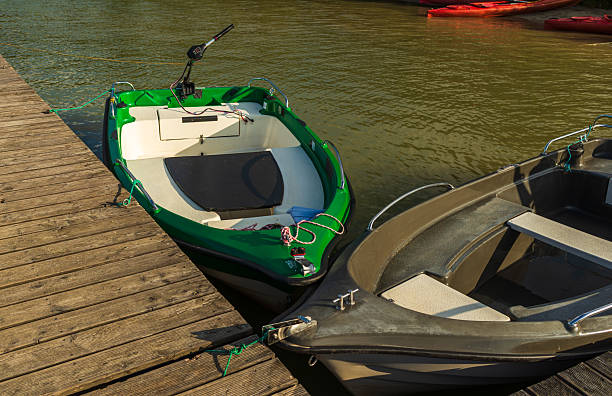 Two small boats moored at a wooden pier on a calm lake, surrounded by a natural setting