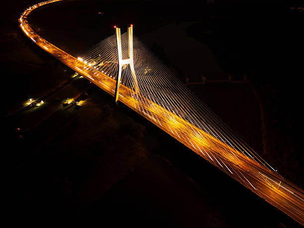 istock Illuminated suspension bridge at night with light trails and distant city lights 2233065038