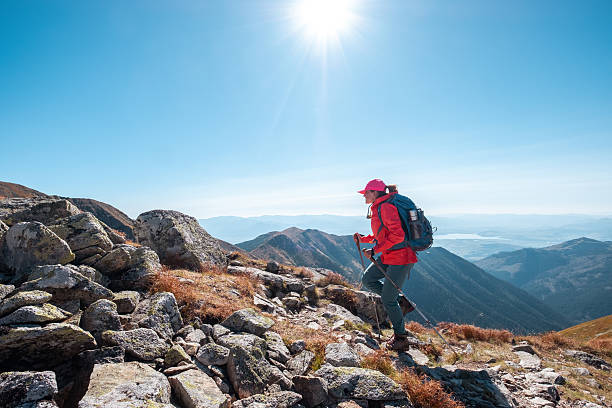 istock Backpacker woman in bright red jacket walking by mountain range using trekking poles with Liptov valley background, Western Tatras, Slovakia. Active people and European hiking tourism concept image 2233071377