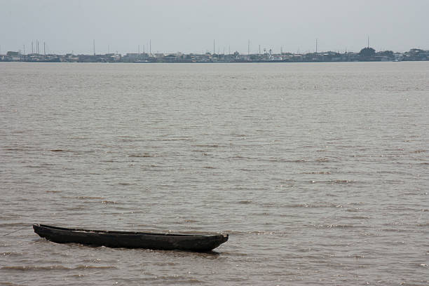 Traditional canoe floating on the calm waters of the Guayas River near Santay Island, with the cityscape of Guayaquil in the background, showcasing the blend of nature and urban life in Ecuador