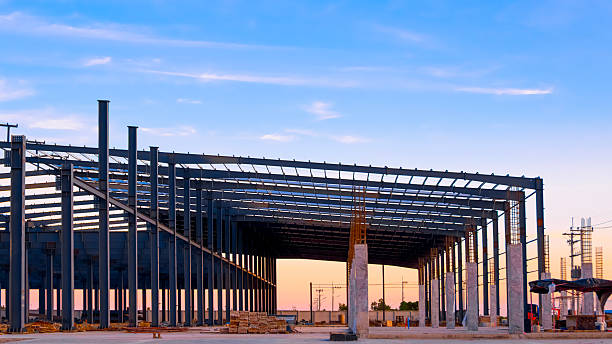 istock Silhouette factory industrial building structure with metal columns and roof beam framework in construction site against evening sky background 2233079209