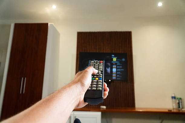 istock Hand holding remote control changing television channel at home 2233079667