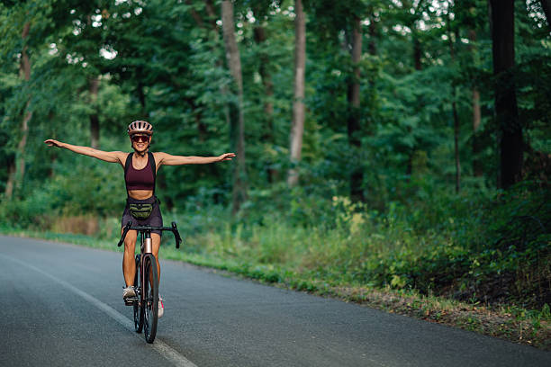 Young woman wearing a helmet and sportswear cycling swiftly on a road bike through an urban landscape, showcasing speed and determination