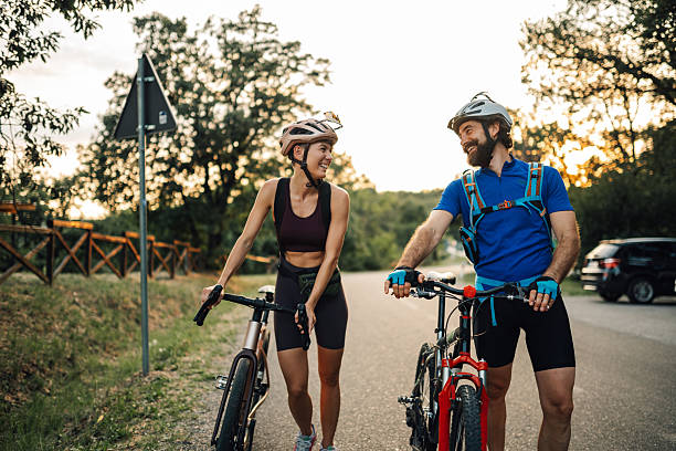 istock Smiling cyclists walking with their bikes on a country road at sunset 2233083314