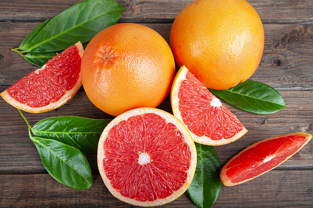 istock Ripe grapefruits with green leaves on brown rustic wooden table 2233083450