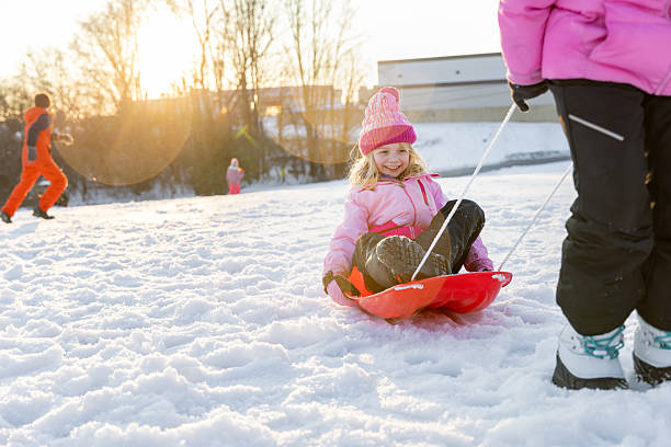 Kids play in snow in winter park. Children playing outdoors on snowy cold day. Boy and girl have fun on sleigh ride. Christmas vacation activity. Outdoor fun by winter weather. Travel with child.