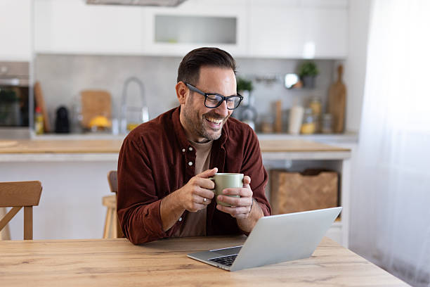 istock Smiling Man Holding Coffee While Working on His Laptop 2233087418
