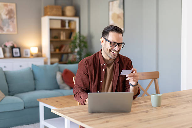 istock Joyful Man Using Credit Card for Online Shopping at Home 2233087421