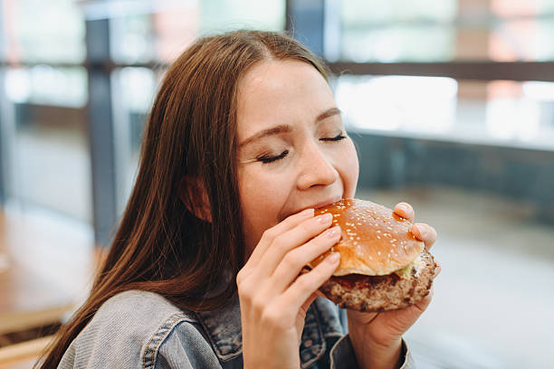 istock hamburger in hands, closeup view, young woman eats hamburger 2233087890