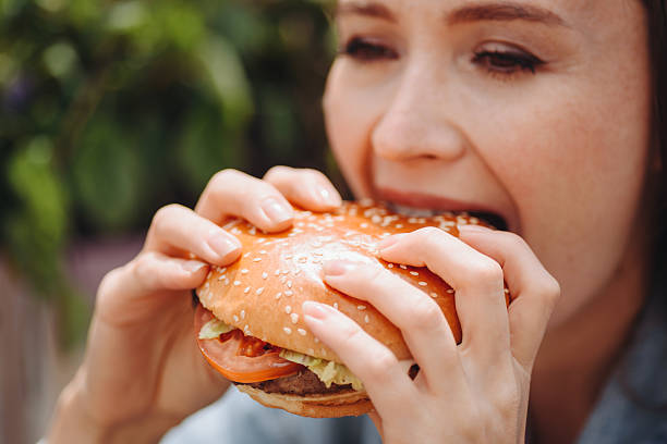 istock hamburger in hands, closeup view, young woman eats hamburger 2233087893