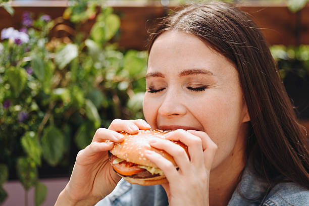 istock hamburger in hands, closeup view, young woman eats hamburger 2233087894