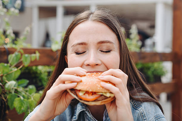 istock hamburger in hands, closeup view, young woman eats hamburger 2233087895