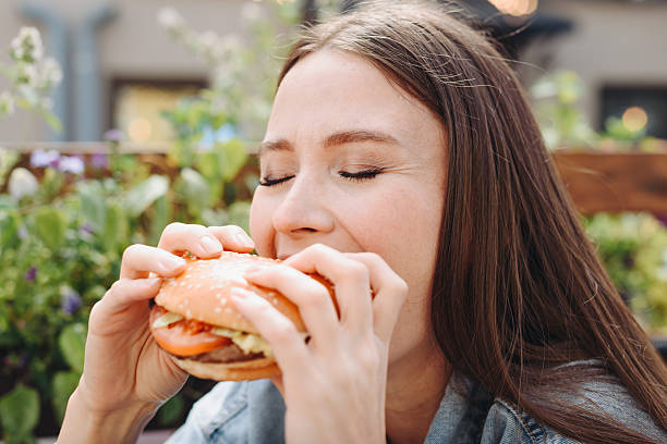 istock hamburger in hands, closeup view, young woman eats hamburger 2233087897