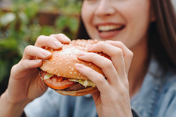 istock hamburger in hands, closeup view, young woman eats hamburger 2233087899