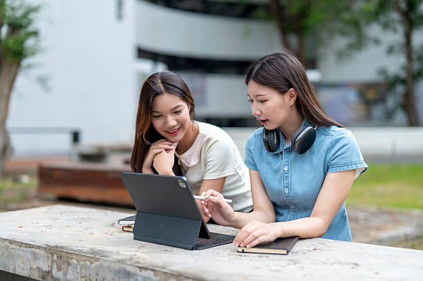istock Two young female university students studying together using digital tablet outdoors 2233091229