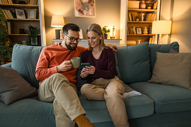 istock Happy young couple using smart phone together at home. 2233099416