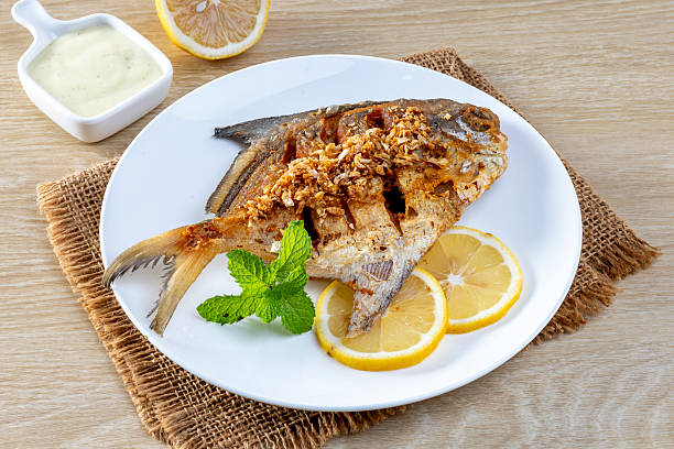 istock Fried sea bass with garlic on a white plate 2233100993
