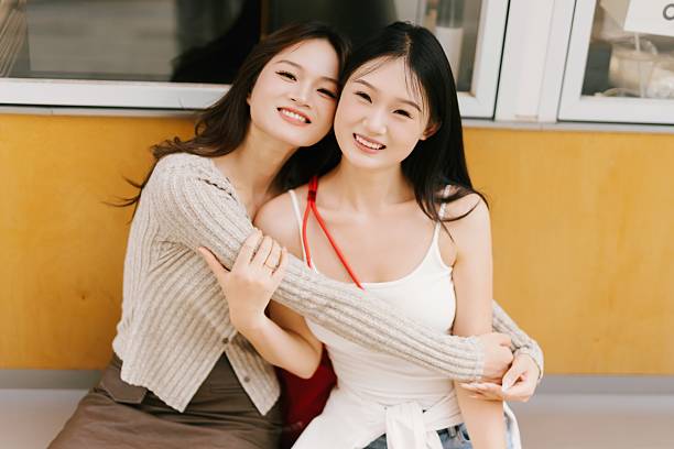 Two young Asian women are holding hands