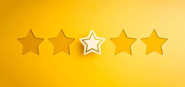 istock Single wooden star placed among empty star cutouts on yellow background represents one-star rating, poor customer satisfaction, product review, low service quality, and negative user experience. 2233104541