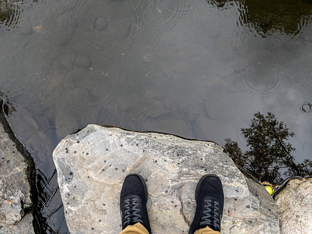 Feet standing on a rock overlooking calm water, enjoying the peaceful nature