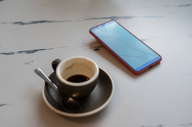 cracked screen smart phone with coffee cup