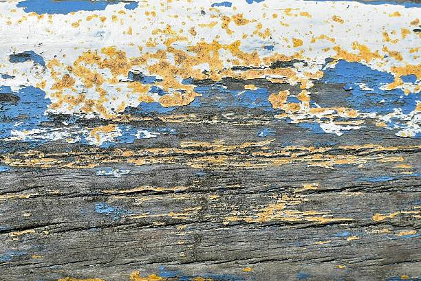 Old peeling blue, white and yellow paint on weathered wood to illustrate DIY and home renovation.