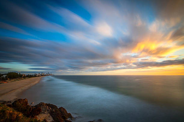 Colourful sunrise over an Australian rocky beach with long exposure to smooth out the ocean to create calm scene, serene and dramatic landscape.